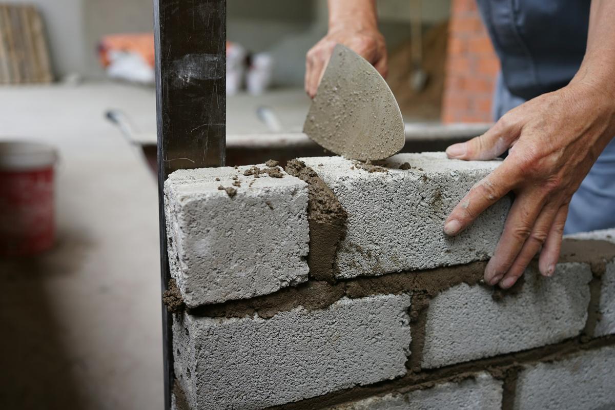 Close view of a mason applying mortar to concrete blockwork