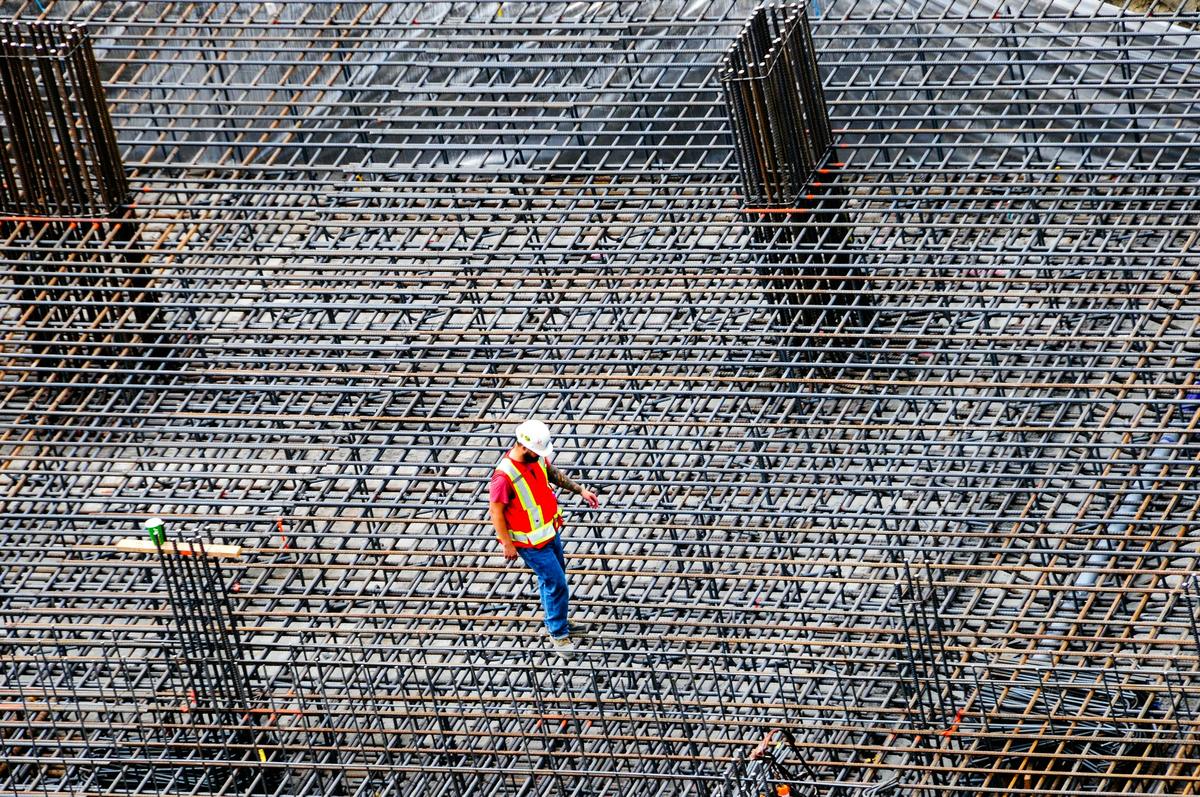 Construction worker inspecting steel reinforcement mesh before a concrete pour