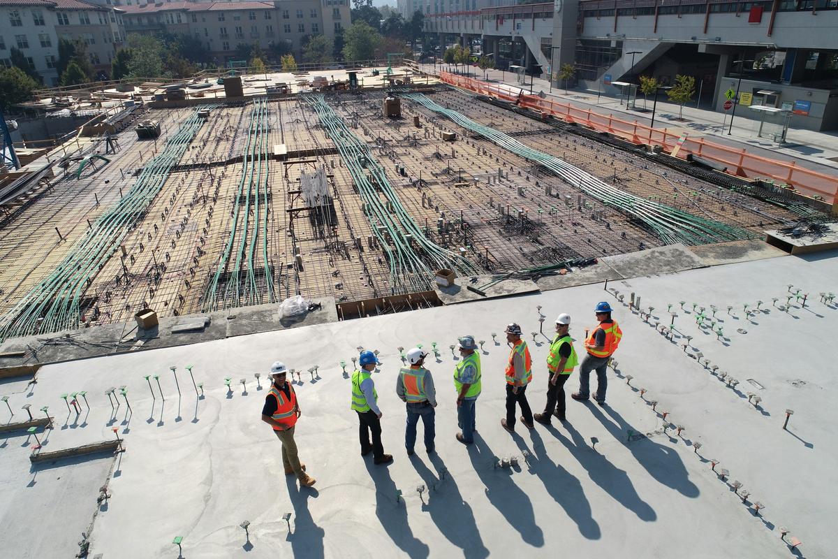 Construction professionals in high-visibility vests standing together on a large building site