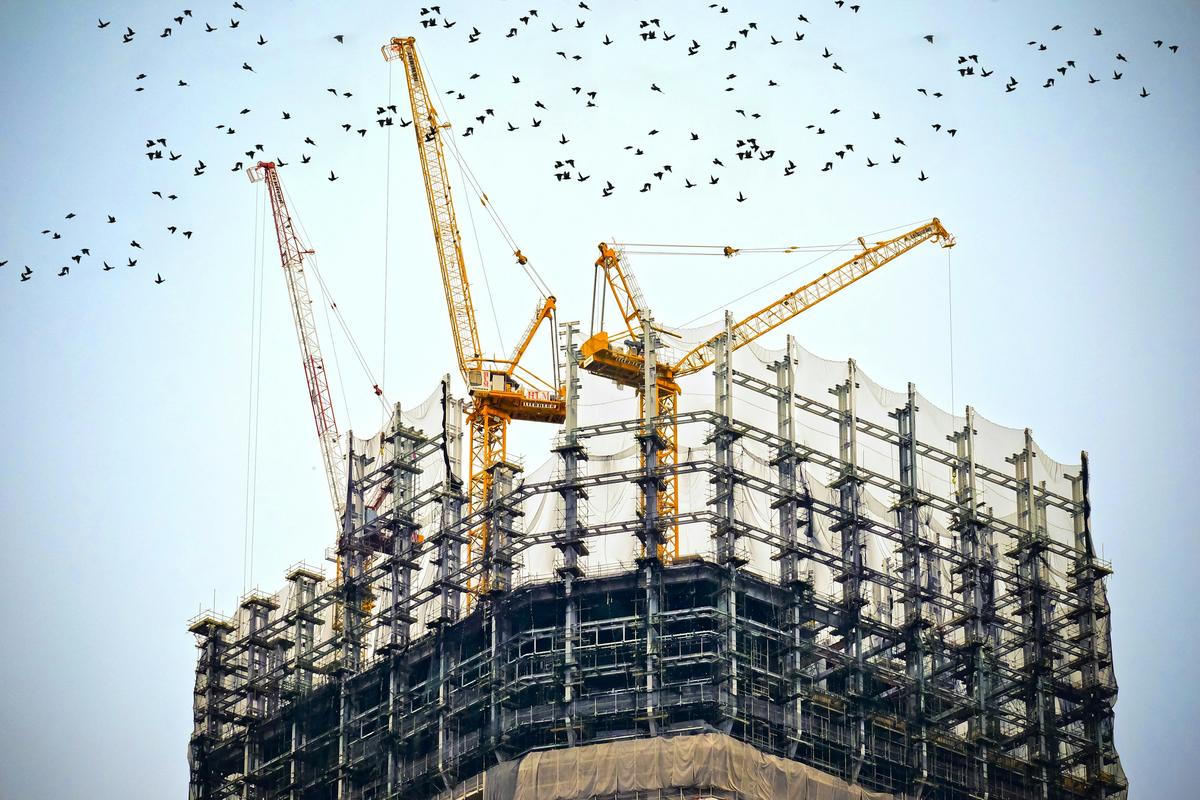 Tower cranes working above the upper floors of a building under construction