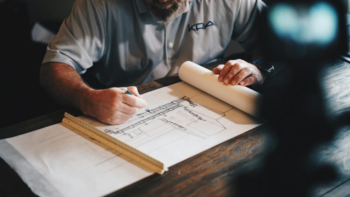 Architect drafting a building plan with pencil and scale ruler