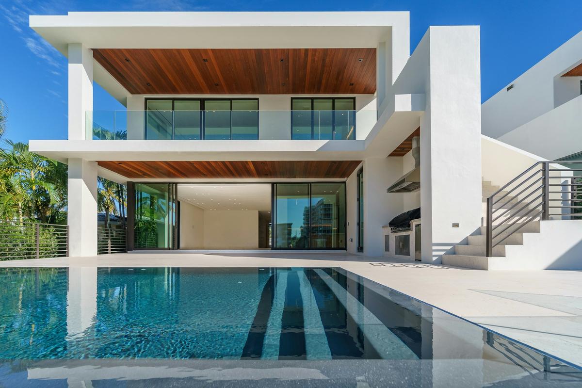 Modern white residence with timber soffits overlooking a swimming pool