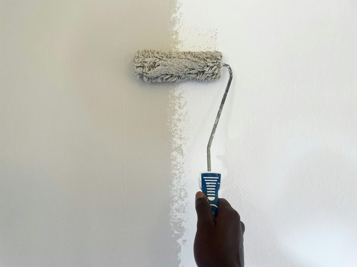 Painter applying a fresh coat to a wall with a paint roller